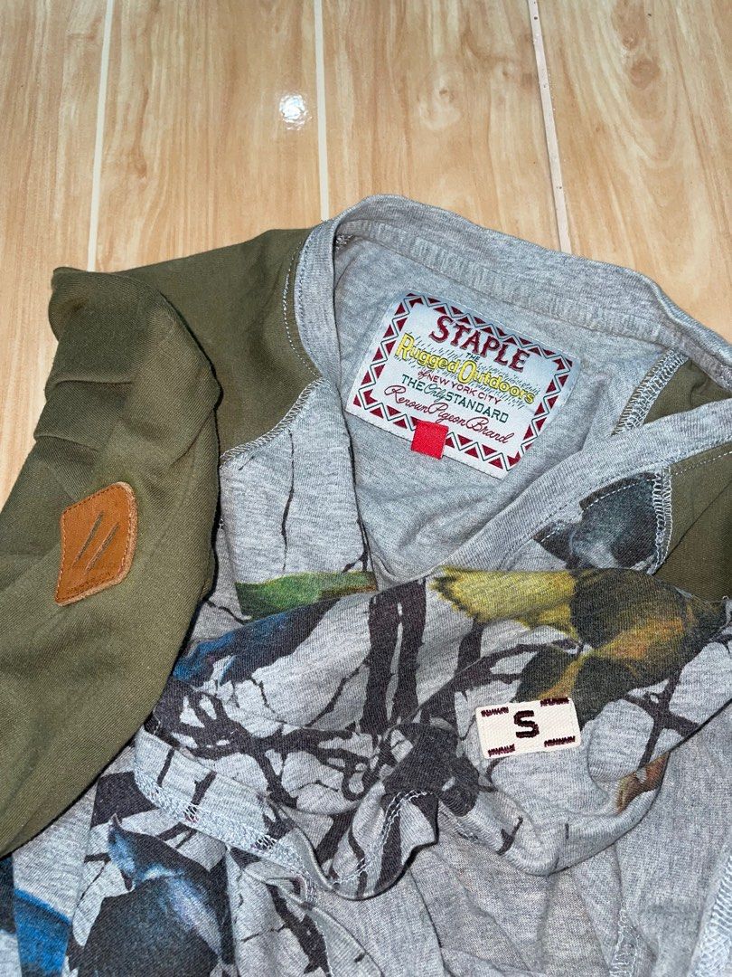 Long Sleeve Shirt with Bird Print (Category: Longsleeves) located in Manila. Submitted by ralph90755 (Listing ID 1408066801, Image 2). Description: - Long-sleeved shirt - Features a unique bird and tree branch print - Olive green sleeves - Gray body - Crew neck - Relaxed fit - Gray cuffs on sleeves - Paired with camouflage pants.