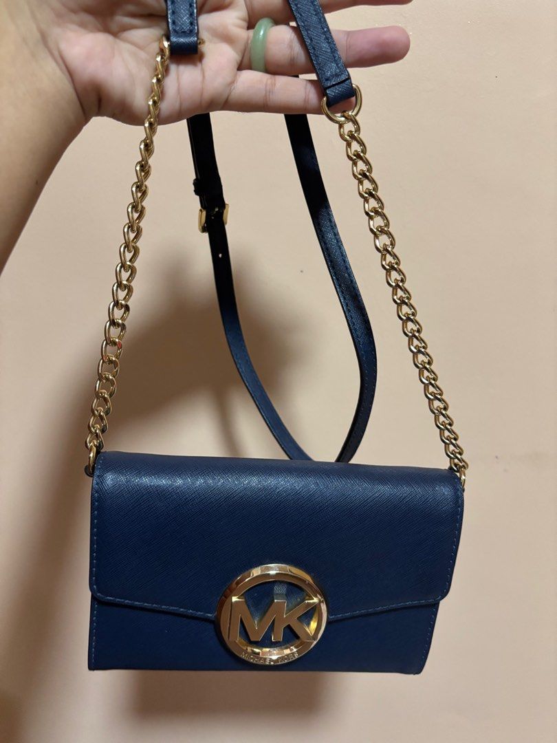 Michael Kors Navy Blue Crossbody Bag (Category: Luxury Bags & Wallets) located in Tacloban City. Submitted by ceegieca (Listing ID 1408042653, Image 2). Description: Navy blue Michael Kors crossbody bag with a gold-tone MK logo. Features a chain strap and a flap closure. The interior is navy blue with the Michael Kors logo visible. The strap is adjustable..