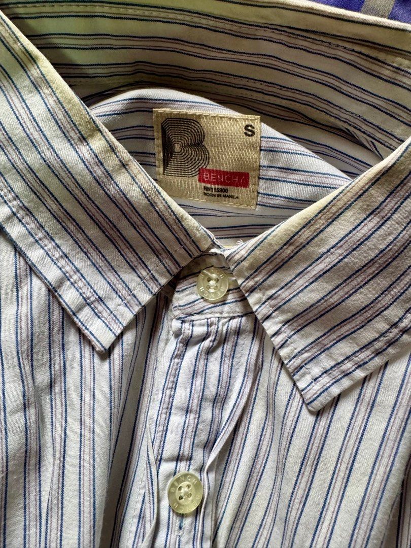 Bench Striped Shirt with Blue Accent (Category: Tshirts & Polo Shirts ) located in Antipolo. Submitted by prelovedbyjerry (Listing ID 1408151628, Image 2). Description: Bench Button Down Shirt Long Sleeves Polo Condition: Used Color: White Stripe with Blue accent Size: Small (W:19 L:27) Mode of Payment: Gcash Delivery: via courier paid by the buyer.