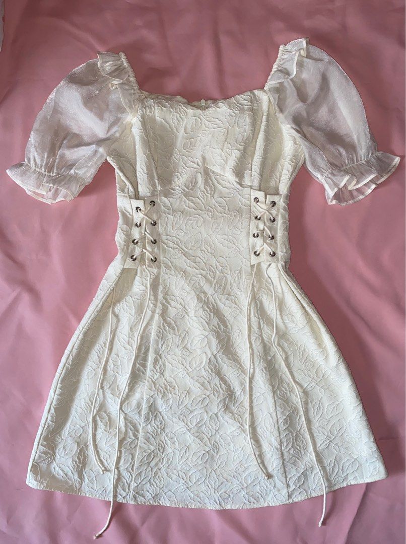 White Lace-Up Mini Dress (Category: Dresses) located in Manila. Submitted by dnllspr (Listing ID 1408143958, Image 1). Description: - White mini dress - Lace-up side detail - Puff sleeves - Textured floral pattern - Size: XS-S - Perfect for special occasions and nights out Location: Tondo, Manila.