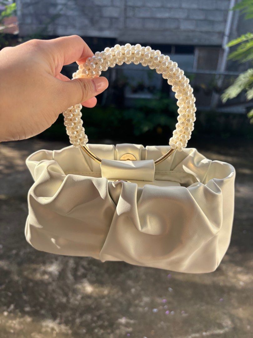 Cream-colored Handbag with Pearl Handle (Category: Luxury Bags & Wallets) located in Clarin. Submitted by declutter_station101 (Listing ID 1408495975, Image 2). Description: - Cream-colored handbag - Unique pearl-beaded handle - Gathered design - Smooth, possibly leather-like material - Gold-colored hardware - Perfect for any occasion.