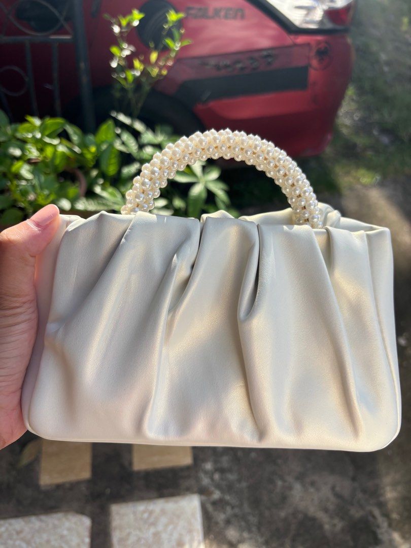 Cream-colored Handbag with Pearl Handle (Category: Luxury Bags & Wallets) located in Clarin. Submitted by declutter_station101 (Listing ID 1408495975, Image 3). Description: - Cream-colored handbag - Unique pearl-beaded handle - Gathered design - Smooth, possibly leather-like material - Gold-colored hardware - Perfect for any occasion.