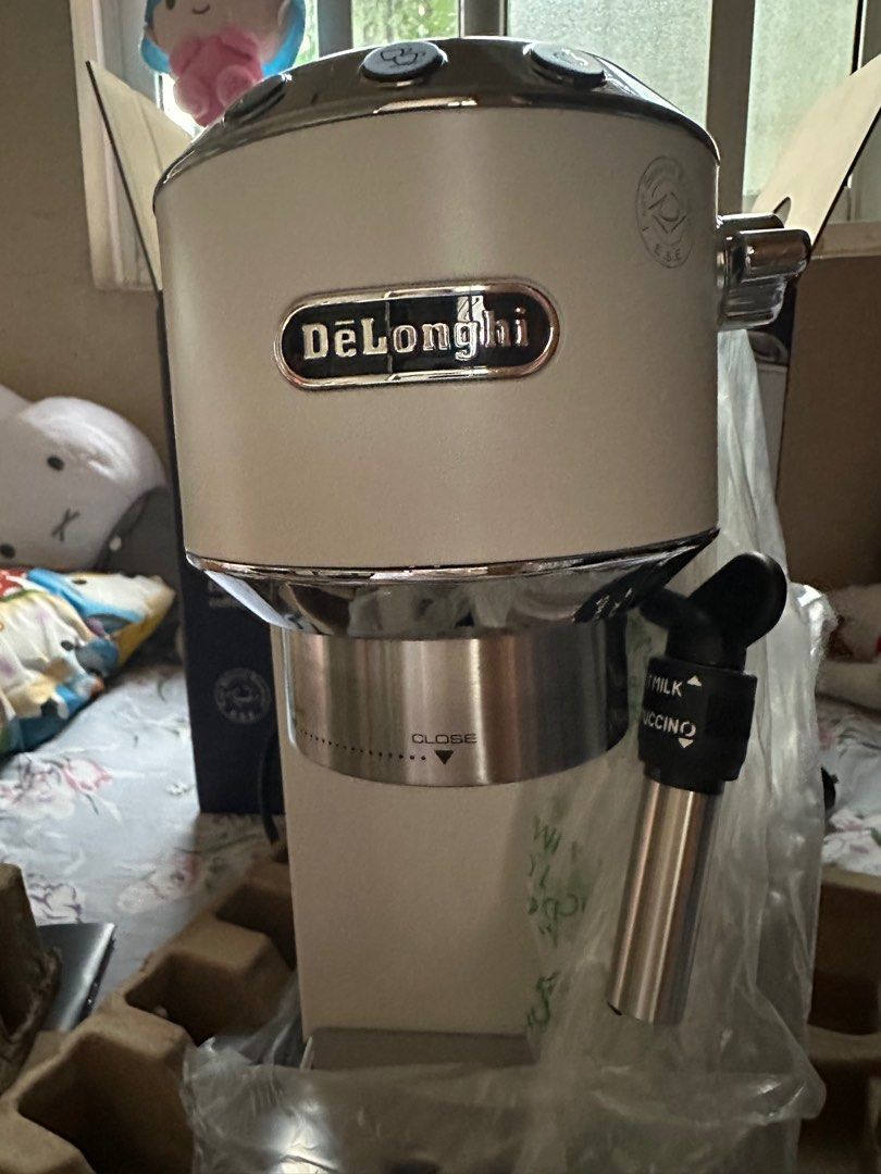 DeLonghi Dedica Style Espresso Coffee Maker (Category: Coffee Machines & Makers) located in Manila. Submitted by konami_bjork (Listing ID 1408456406, Image 1). Description: Brand New DeLonghi Dedica Style espresso and cappuccino coffee maker. Includes a descaler for coffee machines. Comes with accessories and manuals. Features a milk frothing wand for creating cappuccinos. The machine is white and silver in color. Includes the original box and pa
