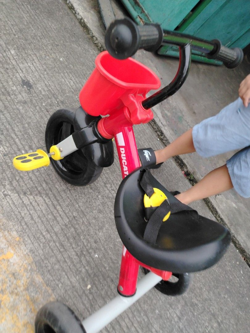 Ducati Tricycle for Kids (Category: Motorbikes for Sale) located in Manila. Submitted by Sissylove12 (Listing ID 1408383272, Image 2). Description: Red Ducati tricycle with black wheels and a small basket. Features yellow pedals and a black seat. The handlebars are black. Suitable for young children..