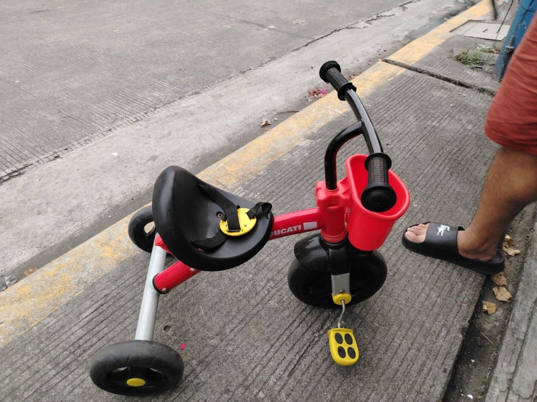Ducati Tricycle for Kids (Category: Motorbikes for Sale) located in Manila. Submitted by Sissylove12 (Listing ID 1408383272, Image 3). Description: Red Ducati tricycle with black wheels and a small basket. Features yellow pedals and a black seat. The handlebars are black. Suitable for young children..