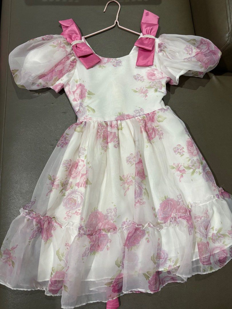 Floral Dress with Bows (Category: Babies & Kids Fashion) located in Clarin. Submitted by declutter_station101 (Listing ID 1408436377, Image 3). Description: - White dress with pink floral design - Puffy sleeves - Pink bows on shoulders - Matching pink sash - Ruffled hem - Perfect for special occasions.