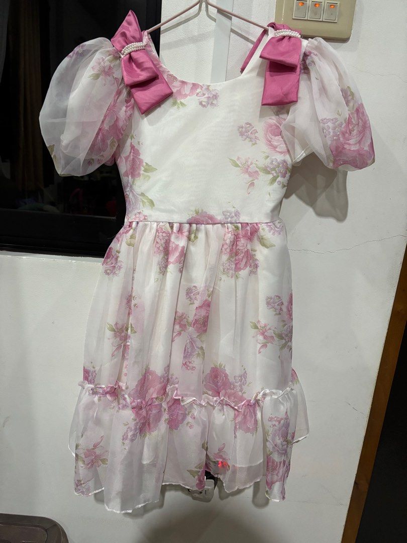 Floral Dress with Bows (Category: Babies & Kids Fashion) located in Clarin. Submitted by declutter_station101 (Listing ID 1408436377, Image 1). Description: - White dress with pink floral design - Puffy sleeves - Pink bows on shoulders - Matching pink sash - Ruffled hem - Perfect for special occasions.