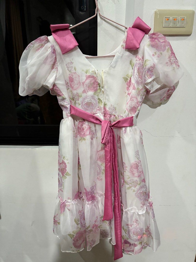 Floral Dress with Bows (Category: Babies & Kids Fashion) located in Clarin. Submitted by declutter_station101 (Listing ID 1408436377, Image 2). Description: - White dress with pink floral design - Puffy sleeves - Pink bows on shoulders - Matching pink sash - Ruffled hem - Perfect for special occasions.