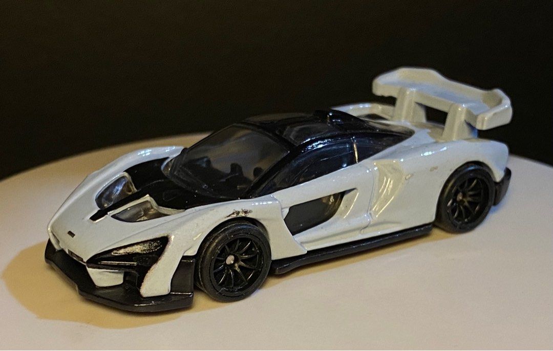 Hot Wheels McLaren Senna (Category: Vehicle & Diecast Models) located in Agoo. Submitted by collect12 (Listing ID 1408430783, Image 1). Description: - Hot Wheels McLaren Senna diecast car - Color: White and black - Features black wheels - Includes a rear wing - Detailed design with visible headlights - Black roof - Perfect for collectors.