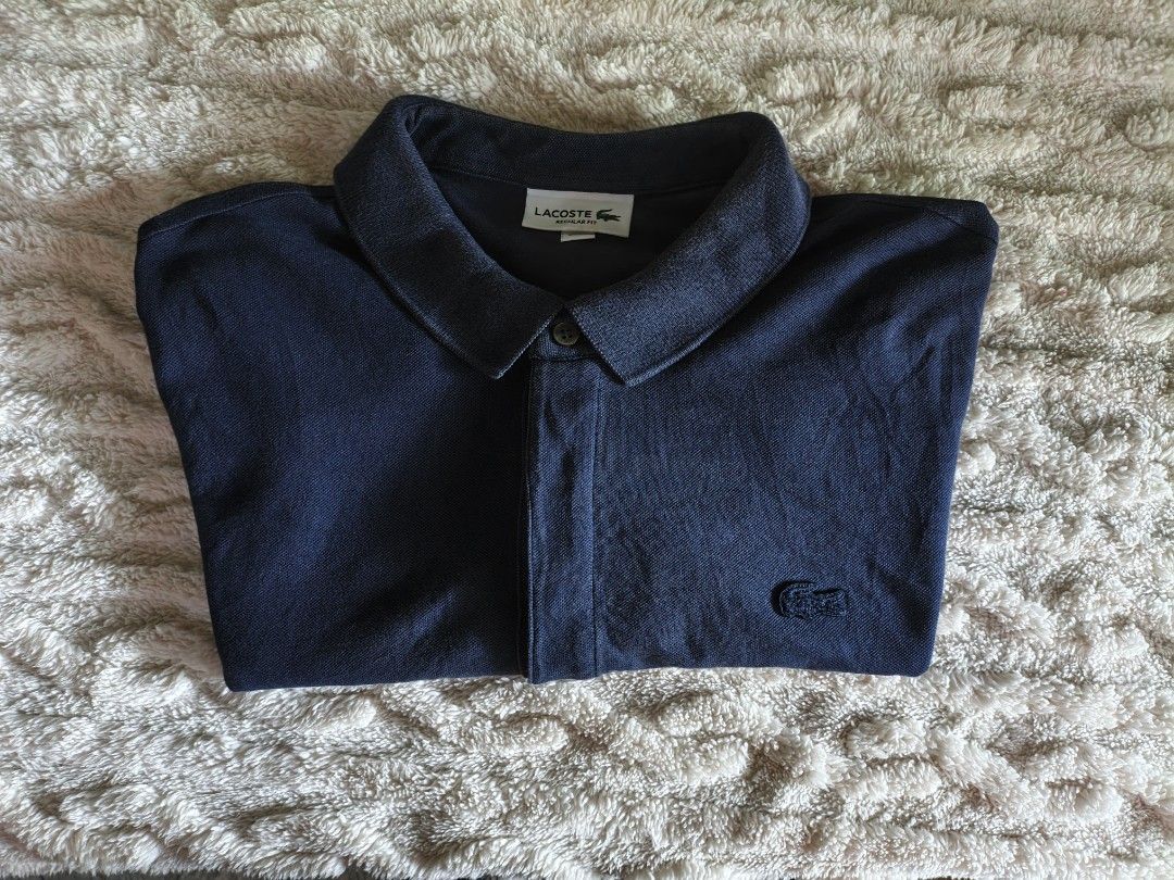 Lacoste Navy Blue Polo Shirt (Category: Tshirts & Polo Shirts ) located in Butuan. Submitted by luxestreet04 (Listing ID 1408320872, Image 1). Description: - Navy blue Lacoste polo shirt - Features the iconic Lacoste logo - Classic polo collar and button-up placket - Made of soft, textured fabric - Perfect for casual or smart-casual outfits.