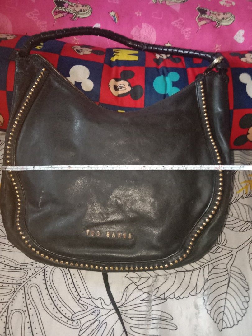 Ted Baker Black Studded Hobo Bag (Category: Luxury Bags & Wallets) located in Bulacan. Submitted by chubbylicious (Listing ID 1408386993, Image 2). Description: - Black Ted Baker hobo bag - Gold-tone stud details - Braided handle - Secure zip closure - Patterned interior lining - Made from genuine leather - Includes interior pockets - Features the Ted Baker logo.