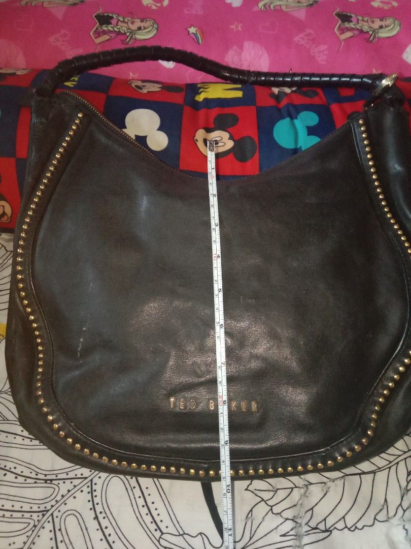 Ted Baker Black Studded Hobo Bag (Category: Luxury Bags & Wallets) located in Bulacan. Submitted by chubbylicious (Listing ID 1408386993, Image 3). Description: - Black Ted Baker hobo bag - Gold-tone stud details - Braided handle - Secure zip closure - Patterned interior lining - Made from genuine leather - Includes interior pockets - Features the Ted Baker logo.