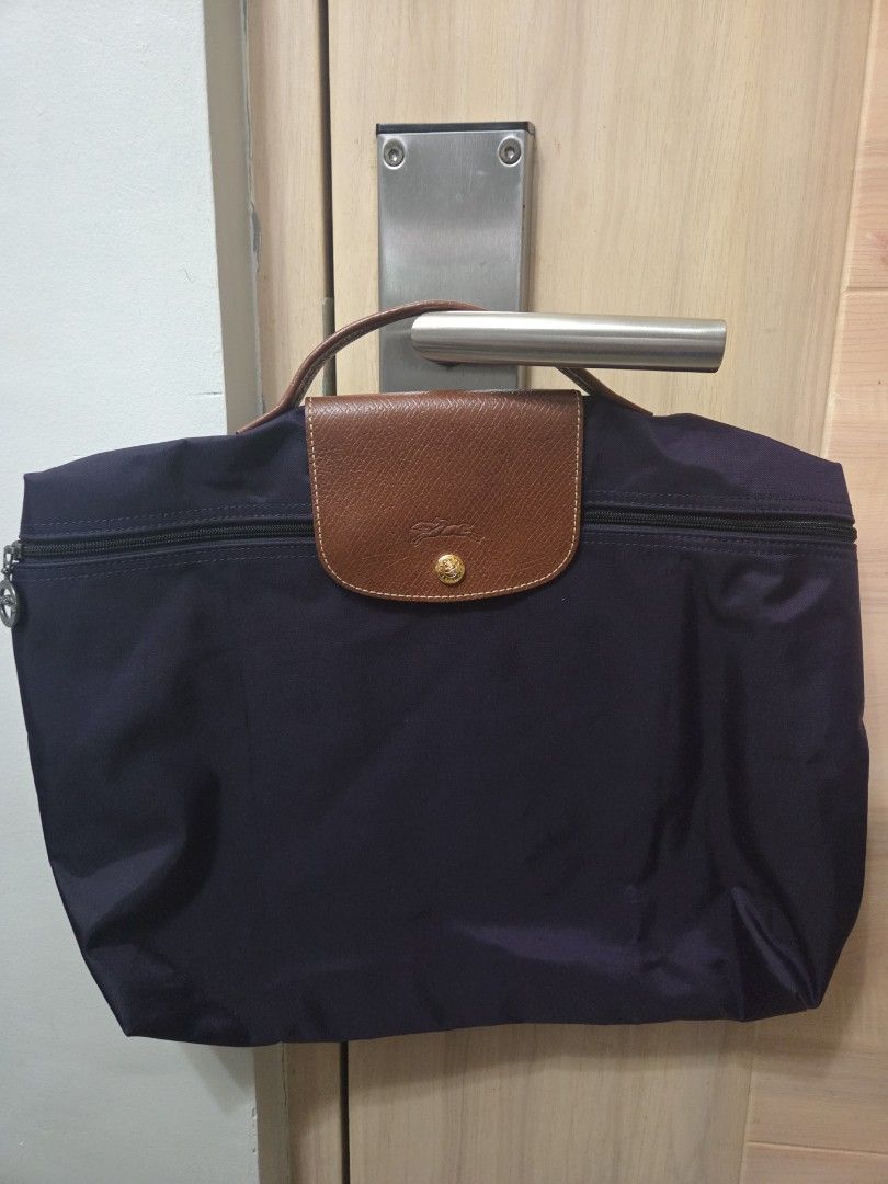 Authentic Longchamp Le Pliage Laptop Bag (Category: Luxury Bags & Wallets) located in Manila. Submitted by sterling_grace (Listing ID 1408567815, Image 1). Description: - Purple, Longchamp Le Pliage laptop bag - Brown leather flap with gold-tone button closure - Zipper closure - Durable nylon material - Classic design - Comes with Longchamp paperbag.
