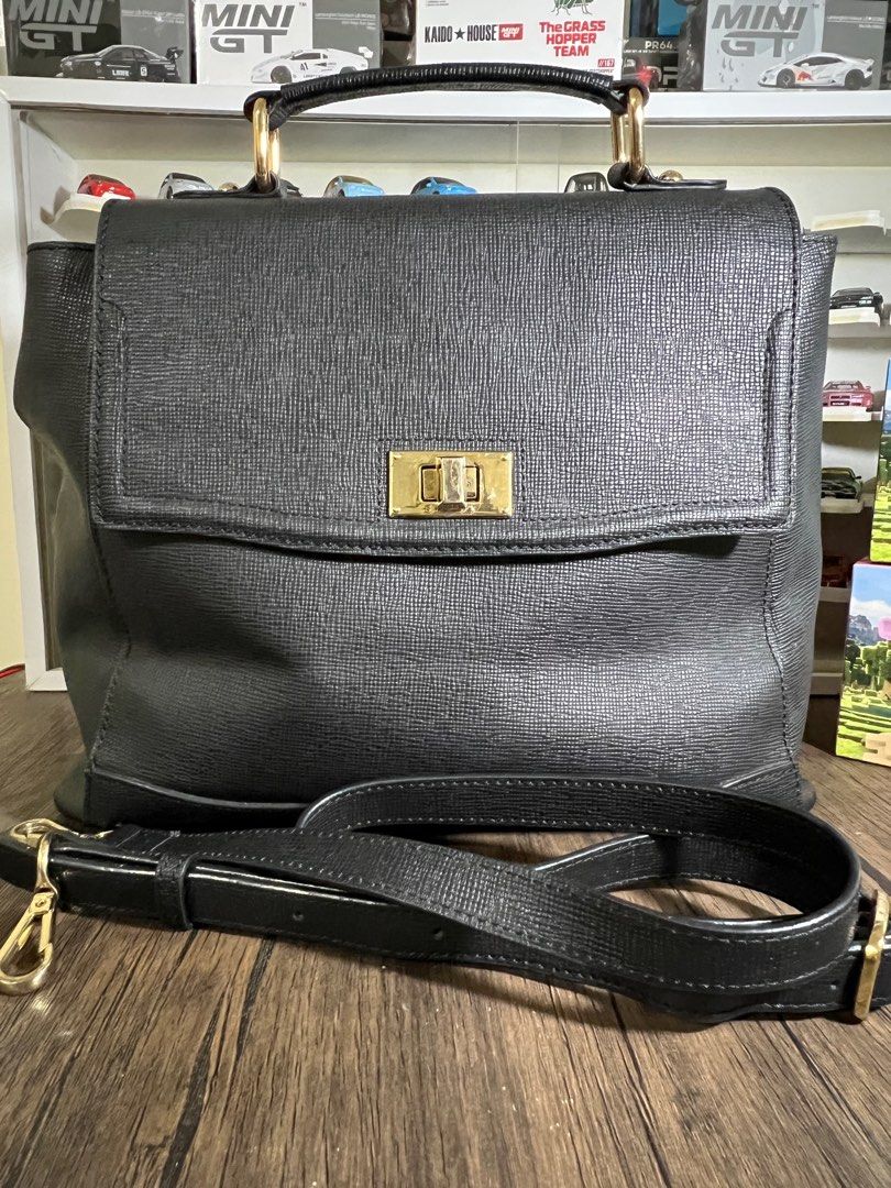 Sisley Satchel Handbag with Shoulder Strap (Category: Shoulder Bags) located in Manila. Submitted by Shib_Shoppe (Listing ID 1408612555, Image 1). Description: - Black satchel handbag - Top handle and detachable shoulder strap - Flap closure with gold-tone clasp - Interior zippered pocket - Exterior zippered pocket - Interior lining with repeating logo pattern - Gold-tone hardware - Preloved: Used but not abused - Minor scratches - check photos.