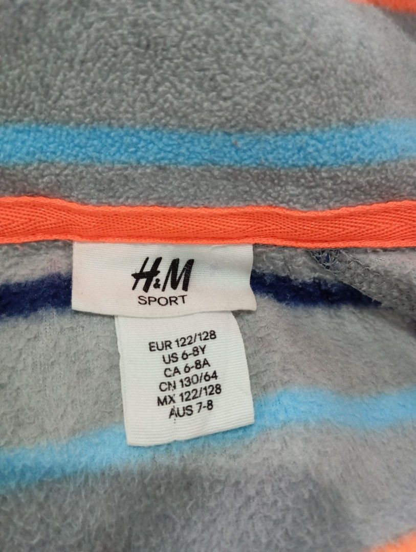 H&M Sport Fleece Jacket (Category: Babies & Kids Fashion) located in Muntinlupa City. Submitted by challasy (Listing ID 1408653703, Image 2). Description: Unsued/New Php 350 H&M Sport fleece jacket with a full zip closure. Features a grey base with blue and orange stripes. The jacket has a stand-up collar and long sleeves. The size is indicated as EUR 122/128, US 6-8Y, CA 6-8A, CN 130/64, MX 122/128, and AUS 7-8. Muntinlupa City.