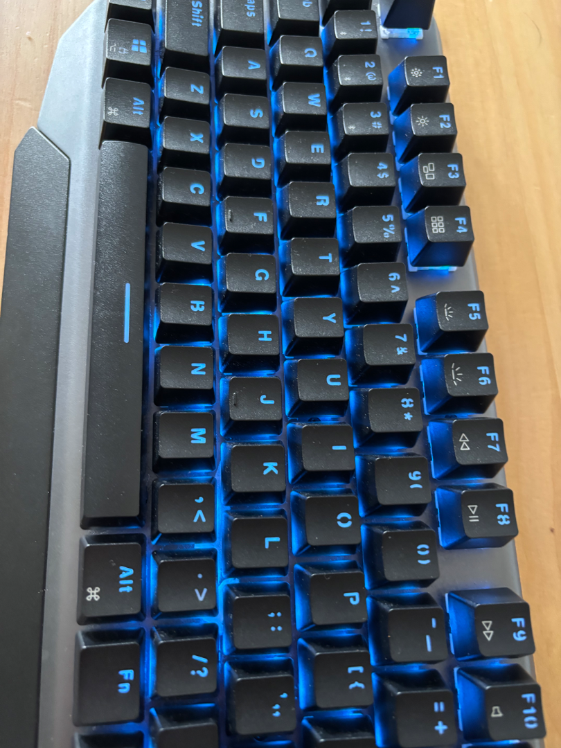 Machenike Mechanical Keyboard with Blue Backlight (Category: Computer Keyboard) located in Caloocan City. Submitted by bloomstoday (Listing ID 1408537010, Image 2). Description: Machenike - Mechanical keyboard - Blue backlight - Standard layout with function keys and number pad - Black keys with white lettering - Includes USB cable - Unique angled design - Shown on a wooden surface.