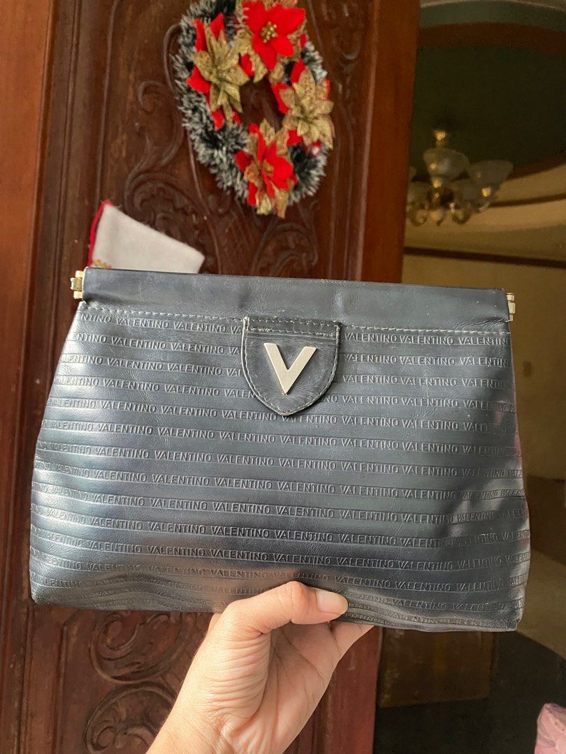 Mario Valentino Black Clutch (Category: Luxury Bags & Wallets) located in Cavite. Submitted by rmquin05 (Listing ID 1408596731, Image 1). Description: - Mario Valentino clutch bag - Black color - Embossed brand name - Flap closure with metal clasp - Interior lining shows wear and tear - Made in Italy.