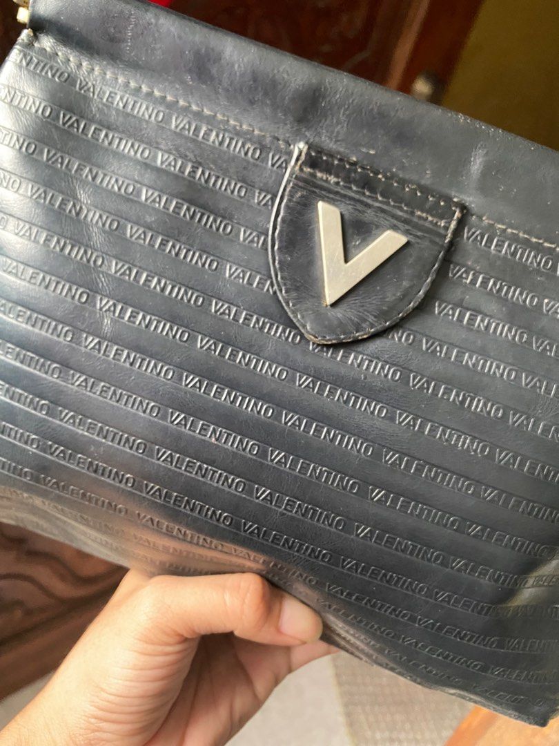 Mario Valentino Black Clutch (Category: Luxury Bags & Wallets) located in Cavite. Submitted by rmquin05 (Listing ID 1408596731, Image 2). Description: - Mario Valentino clutch bag - Black color - Embossed brand name - Flap closure with metal clasp - Interior lining shows wear and tear - Made in Italy.