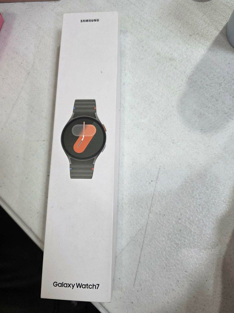 Samsung Galaxy Watch7 (Category: Wearables & Smart Watches) located in Quezon City. Submitted by chaeyoung324 (Listing ID 1408610562, Image 1). Description: - Samsung Galaxy Watch7 - Brand new, sealed in original packaging. - Features a stylish dark-colored band. - Round watch face with a vibrant orange and black color scheme. - White box with Samsung logo and Galaxy Watch7 model name..