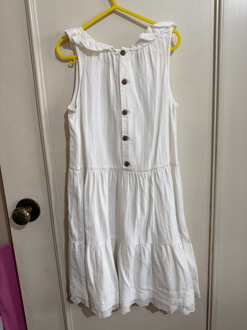 White Sleeveless Tiered Dress (Category: Babies & Kids Fashion) located in Quezon City. Submitted by well.lovedph (Listing ID 1408517793, Image 2). Description: White sleeveless dress with a tiered design. Features a ruffled neckline and decorative buttons down the back. The dress has a textured fabric and a lace trim at the hem. .