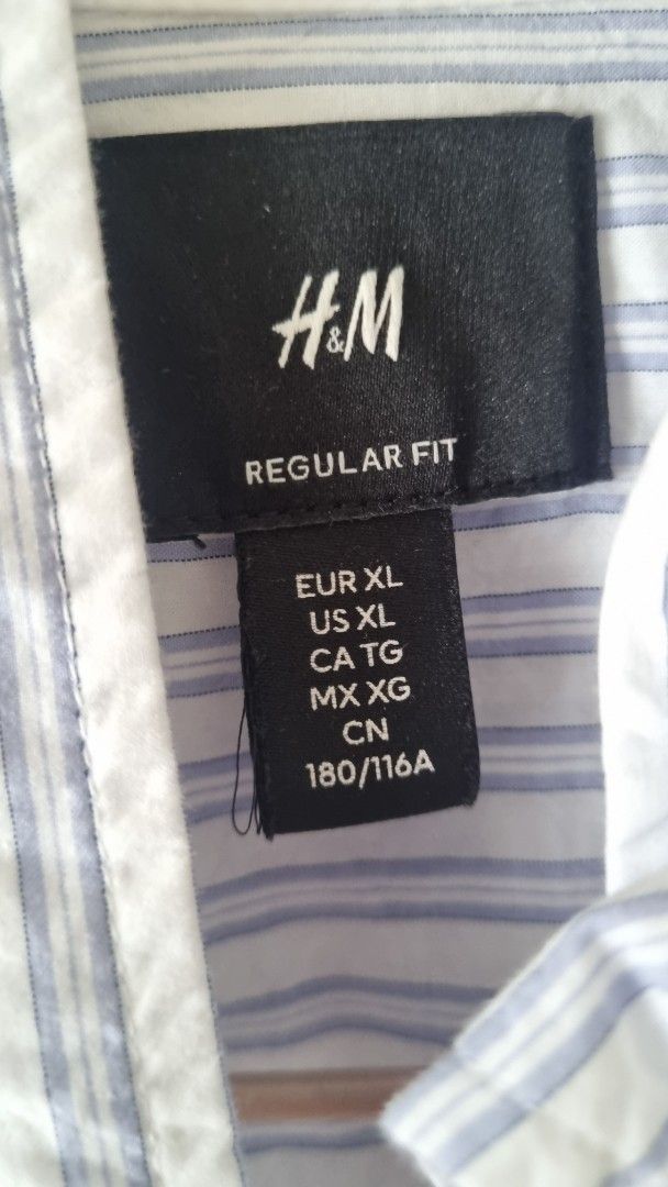H&M Regular Fit Striped Shirt - XL (Category: Tshirts & Polo Shirts ) located in Manila. Submitted by cssunriseph (Listing ID 1408748967, Image 2). Description: H&M Regular Fit shirt in a striped pattern. Features a button-down design with long sleeves. The shirt is a light blue and white color. Size is XL. Made from a lightweight fabric, suitable for casual wear. The shirt has a classic collar and a single chest pocket..