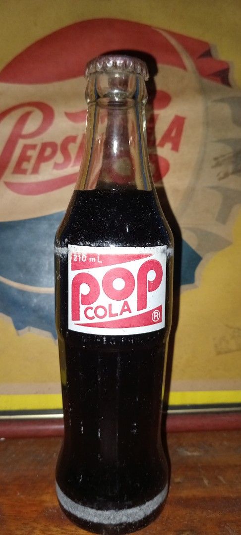 Pop Cola Glass Bottle Original crown and content (Category: Water Bottles & Tumblers) located in Manila. Submitted by iamrich110502 (Listing ID 1408856109, Image 1). Description: - Vintage Pop Cola glass bottle - Features the classic Pop Cola logo - Contains original dark soda - Includes metal cap - 170 mL size.