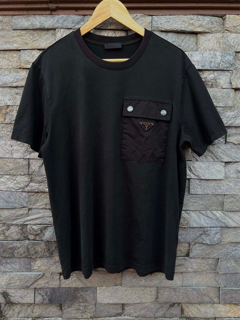 Prada Black Pocket T-shirt (Category: Luxury Apparel) located in Bacolod City. Submitted by novymaesel14868 (Listing ID 1408700556, Image 1). Description: - Prada black t-shirt - Chest pocket with Prada logo - Silver button closure on pocket - Crew neck and short sleeves - Made in Indonesia - Fabric: 100% cotton Size XL Dimes 22x28 Excellent Condition DM to Purchase 📩.
