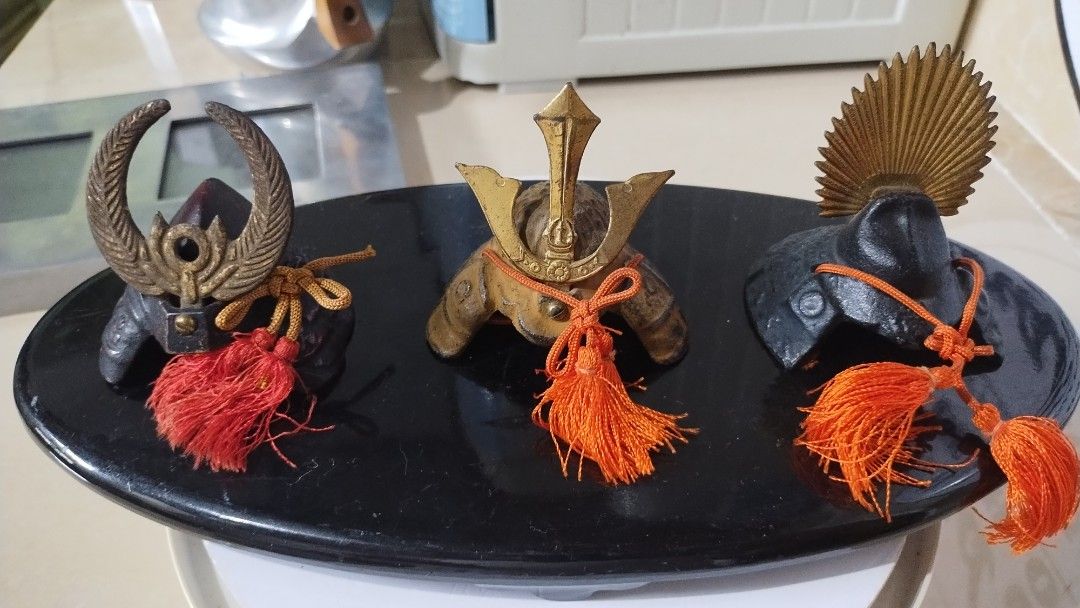 Japanese Samurai Helmet Miniature (Set including Tray) (Category: Vintage Collectibles) located in Parang, Maguindanao. Submitted by lawon_koleksyon (Listing ID 1354551578, Image 1). Description: The image shows three miniature Japanese samurai helmets, likely from the 1980s. They are made of metal and have decorative tassels. These helmets are called kabuto and were part of the samurai armor. .