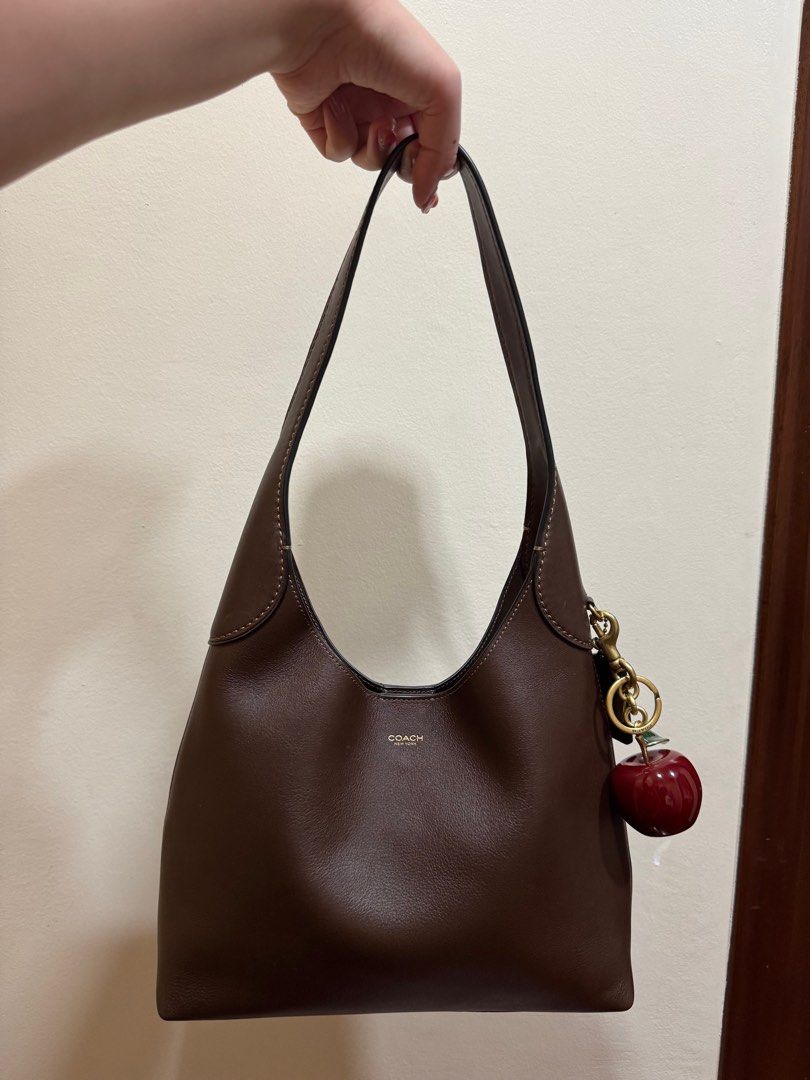 Coach Brooklyn 28 + brass apple charm (Category: Shoulder Bags) located in Makati City. Submitted by _stepau (Listing ID 1359922574, Image 1). Description: Bought in Japan last Dec 2024. Bag is in the Maple color. Will include a Coach brass apple bag charm I bought with the bag!! Comes with the original dust bag. Used together only once. Honest flaws: two small scuff marks from wear by the base of the handles. Not noticeable when wearing. The lea