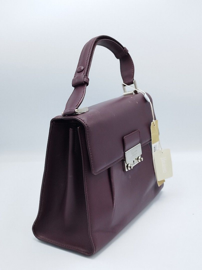 Herno Top handle bag (Category: Luxury Bags & Wallets) located in Quezon City. Submitted by redragtag (Listing ID 1360220324, Image 3). Description: This is a Herno leather top handle structured bag in a deep burgundy color. A luxury brand that has a classic and elegant design. Features a silver-toned hardware logo embossed, two storage compartments, 1 zipoer pocket, 2 open pockets, and center snap button pocket. This is unused item but has stora