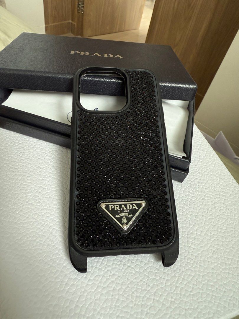 Authentic PRADA swarovski crystal studs case for iPhone 13/iPhone 14 Pro (Category: Cases & Sleeves) located in Makati City. Submitted by akr09 (Listing ID 1360748844, Image 3). Description: Full set with box, cards and receipt Good condition Prada cases for iPhone 13 and iPhone 14 Retail Price: white crystals- 25,000, black crystal case- 50,000 Note: White Crystal Case- with visible tarnishing on prada logo Black Crystal Case- with holes for pho
