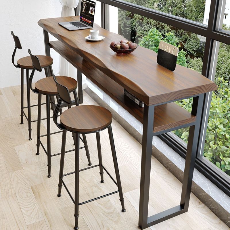 BILLY Rustic Solid Wood Bar Table (Category: Tables & Sets) located in Singapore. Submitted by homejourney.sg (Listing ID 1364098052, Image 2). Description: Redefine your bar area or outdoor lounge with our BILLY bar table. Crafted from pine wood in a beautiful matte walnut finish, its natural wavy edge adds an organic touch to your space. A convenient shelf beneath offers storage space for your laptop and books when entertaining guests. Whether 