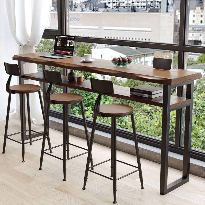BILLY Rustic Solid Wood Bar Table (Category: Tables & Sets) located in Singapore. Submitted by homejourney.sg (Listing ID 1364098052, Image 1). Description: Redefine your bar area or outdoor lounge with our BILLY bar table. Crafted from pine wood in a beautiful matte walnut finish, its natural wavy edge adds an organic touch to your space. A convenient shelf beneath offers storage space for your laptop and books when entertaining guests. Whether 