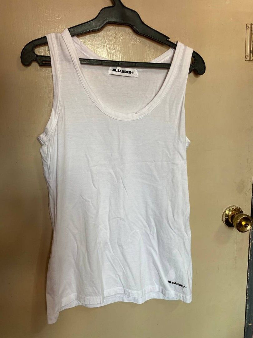 Jill Sander logo-print White tank top (Category: Sleeveless) located in Quezon City. Submitted by queentasha (Listing ID 1365674342, Image 3). Description: Jil Sander logo-print cotton tank top IN SIZE LARGE An ode to Jil Sander's minimalistic aesthetic, this cotton tank top is subtly decorated with a contrasting logo print at the hem. Made in Italy Composition Cotton 100% In GOOD CONDITION NO FLAWS, STAINS JUST NEED TO BE PRESS OR STEAM.