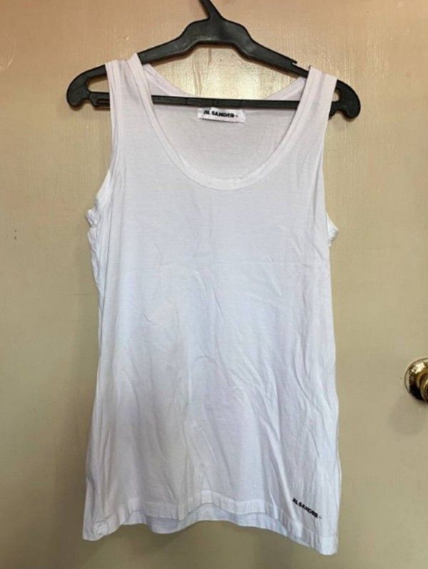 Jill Sander logo-print White tank top (Category: Sleeveless) located in Quezon City. Submitted by queentasha (Listing ID 1365674342, Image 1). Description: Jil Sander logo-print cotton tank top IN SIZE LARGE An ode to Jil Sander's minimalistic aesthetic, this cotton tank top is subtly decorated with a contrasting logo print at the hem. Made in Italy Composition Cotton 100% In GOOD CONDITION NO FLAWS, STAINS JUST NEED TO BE PRESS OR STEAM.