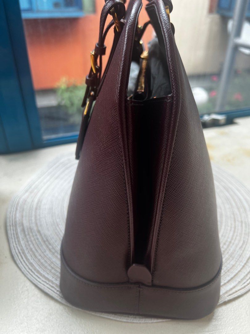 Prada Saffiano Lux tote (Category: Luxury Bags & Wallets) located in San Juan City. Submitted by iambernie (Listing ID 1366443406, Image 3). Description: The stunning promenade tote is high on appeal and style. Dazzling in a gorgeous granato (maroon )shade, the bag is crafted from saffiano leather and features 2 rolled handles and a detachable shoulder strap. The snap button leads way to a nylon lined interior with enough space for your essential