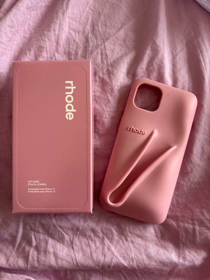 Authentic Rhode iPhone 13 Lip Case in Ribbon (Category: Cases & Sleeves) located in Makati City. Submitted by michi_ (Listing ID 1362537485, Image 1). Description: Original! Bought it during my last trip to NY from the rhode website. Out of stock already :( has some flaws: - two small stains from a henna tattoo haha :((( maybe you can take it off pa - small unnoticeable tear on the corner (came like that) RFS: Upgraded to a new phone.