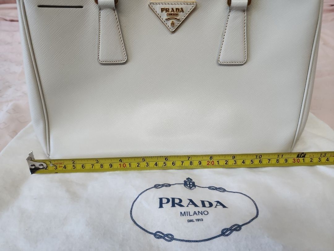 Authentic Prada Saffiano Leather Bag, Medium, Top Handle Bag (Category: Bags & Wallets) located in Singapore. Submitted by j-dpose (Listing ID 1367387218, Image 3). Description: Elevate your style with this preloved Authentic Prada Saffiano Leather Bag in medium size—a timeless classic that’s perfect for any occasion! Crafted from luxurious Saffiano leather, this top handle bag exudes elegance and durability. Its spacious interior and structured 