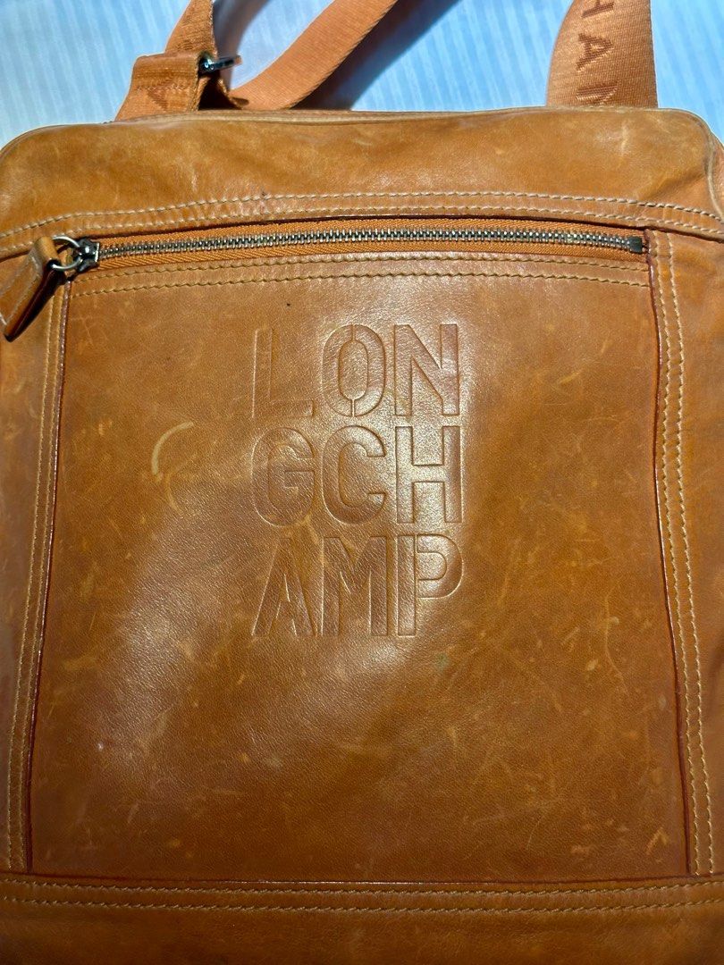 LONGCHAMP Leather Messenger Bag Orange (Category: Luxury Bags & Wallets) located in Manila. Submitted by marcgm.777 (Listing ID 1367661018, Image 3). Description: LONGCHAMP Cavalier Embossed Logo Leather Messenger PHP 3500 AUTHENTIC 💯 and pre-loved messenger/sling bag for men. Condition of the item is well-loved and well-used, with some visible scratches on closeup look. Dimensions in cm: (WxHxD) 25 × 29 × 3 Strap length: 75 - 135 cm Color: Tan 