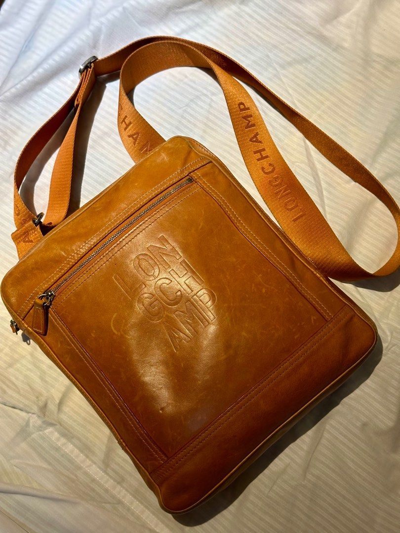 LONGCHAMP Leather Messenger Bag Orange (Category: Luxury Bags & Wallets) located in Manila. Submitted by marcgm.777 (Listing ID 1367661018, Image 1). Description: LONGCHAMP Cavalier Embossed Logo Leather Messenger PHP 3500 AUTHENTIC 💯 and pre-loved messenger/sling bag for men. Condition of the item is well-loved and well-used, with some visible scratches on closeup look. Dimensions in cm: (WxHxD) 25 × 29 × 3 Strap length: 75 - 135 cm Color: Tan 