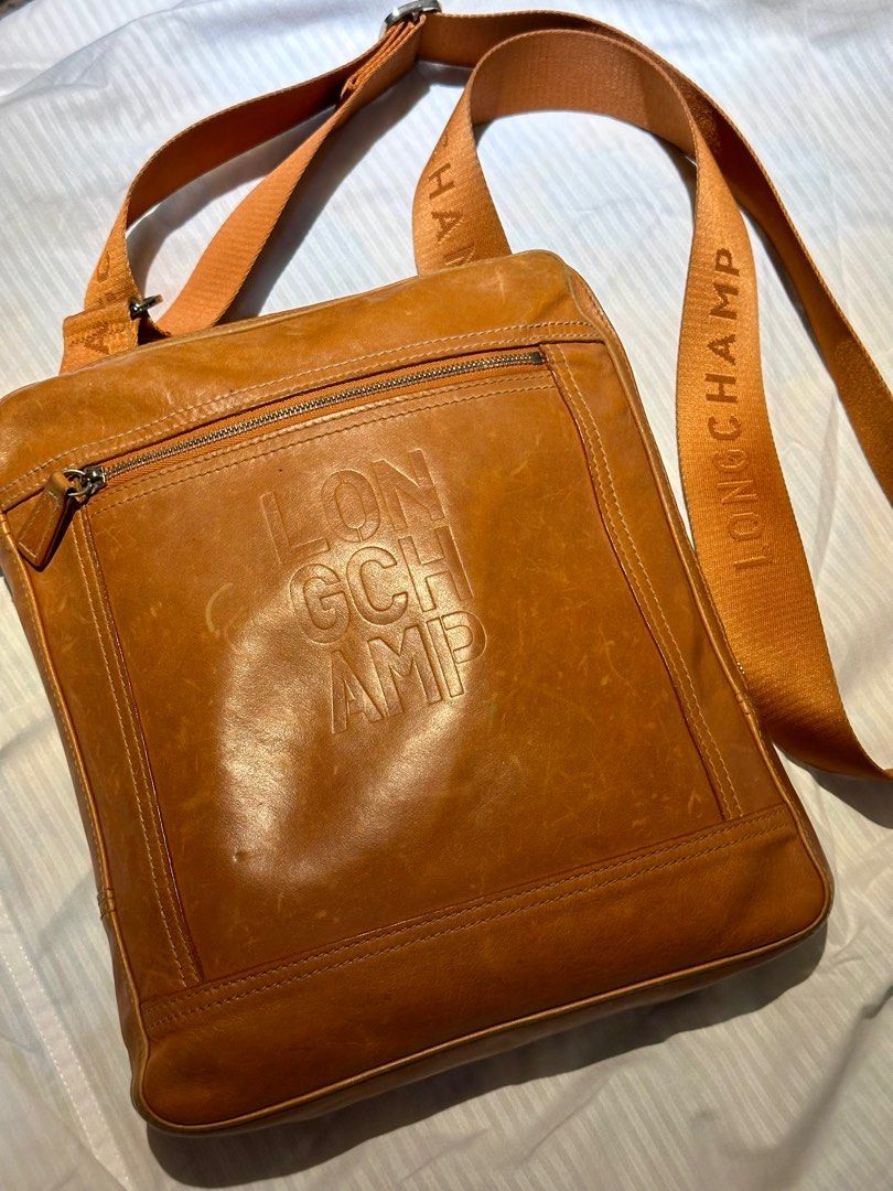LONGCHAMP Leather Messenger Bag Orange (Category: Luxury Bags & Wallets) located in Manila. Submitted by marcgm.777 (Listing ID 1367661018, Image 2). Description: LONGCHAMP Cavalier Embossed Logo Leather Messenger PHP 3500 AUTHENTIC 💯 and pre-loved messenger/sling bag for men. Condition of the item is well-loved and well-used, with some visible scratches on closeup look. Dimensions in cm: (WxHxD) 25 × 29 × 3 Strap length: 75 - 135 cm Color: Tan 