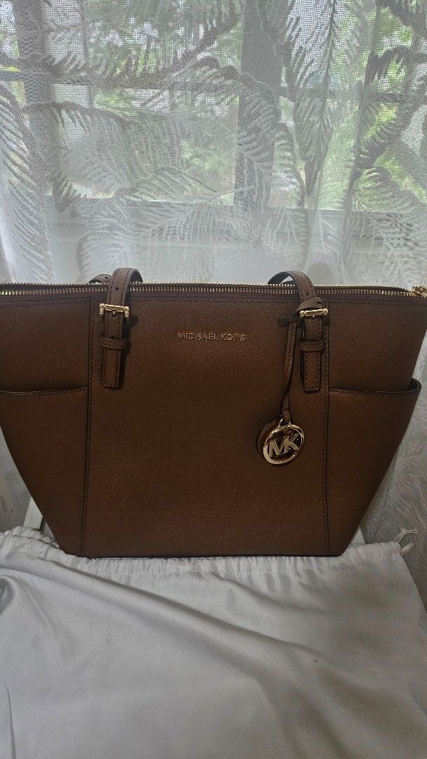 Original Michael Kors Charlotte Tote Bag (Category: Luxury Bags & Wallets) located in Pasig City. Submitted by thegarmentstale (Listing ID 1367714840, Image 1). Description: Original from UK with Tag Price Dust Bag Included Gold Toned Hardware Michael Kors Logo at Front 2 Slip-in Back Pocket On Side 1 MK Circle Charm Zip Top Closure Custom Fabric Lining 2 Slip-in Pockets 1 Zipped Pocket 15"(Top) 11"(Bottom) x 10"(H) x 4.5"(D) Straps: 9.5".