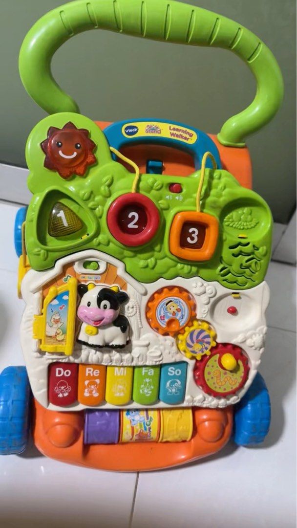 VTech Learning Walker - Baby Walker with Interactive Features (Category: Infant Playtime) located in Singapore. Submitted by tdnpbd7mx407230 (Listing ID 1374450221, Image 1). Description: This is a very well-used VTech Learning Walker. It's a great toy for babies who are learning to walk. It has a lot of interactive features, including a piano, numbers, and shapes. It's in good working condition, but it does show some signs of wear and tear. It's