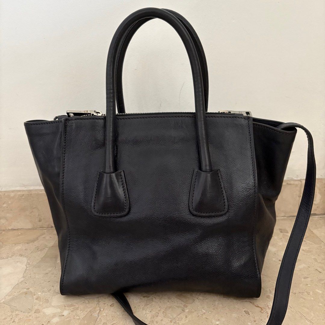 Authentic PRADA Glace Calf Leather Twin Pocket Double Handle Tote Bag (Category: Bags & Wallets) located in Singapore. Submitted by highsociety.sg (Listing ID 1376038832, Image 2). Description: The Prada Glace Calf Leather Twin Pocket Double Handle Tote Bag is one sophisticated piece. This spacious tote has the capability to hold all your daily essentials and more. It is made of gorgeous glazed leather with two rolled top handles, a removable sho