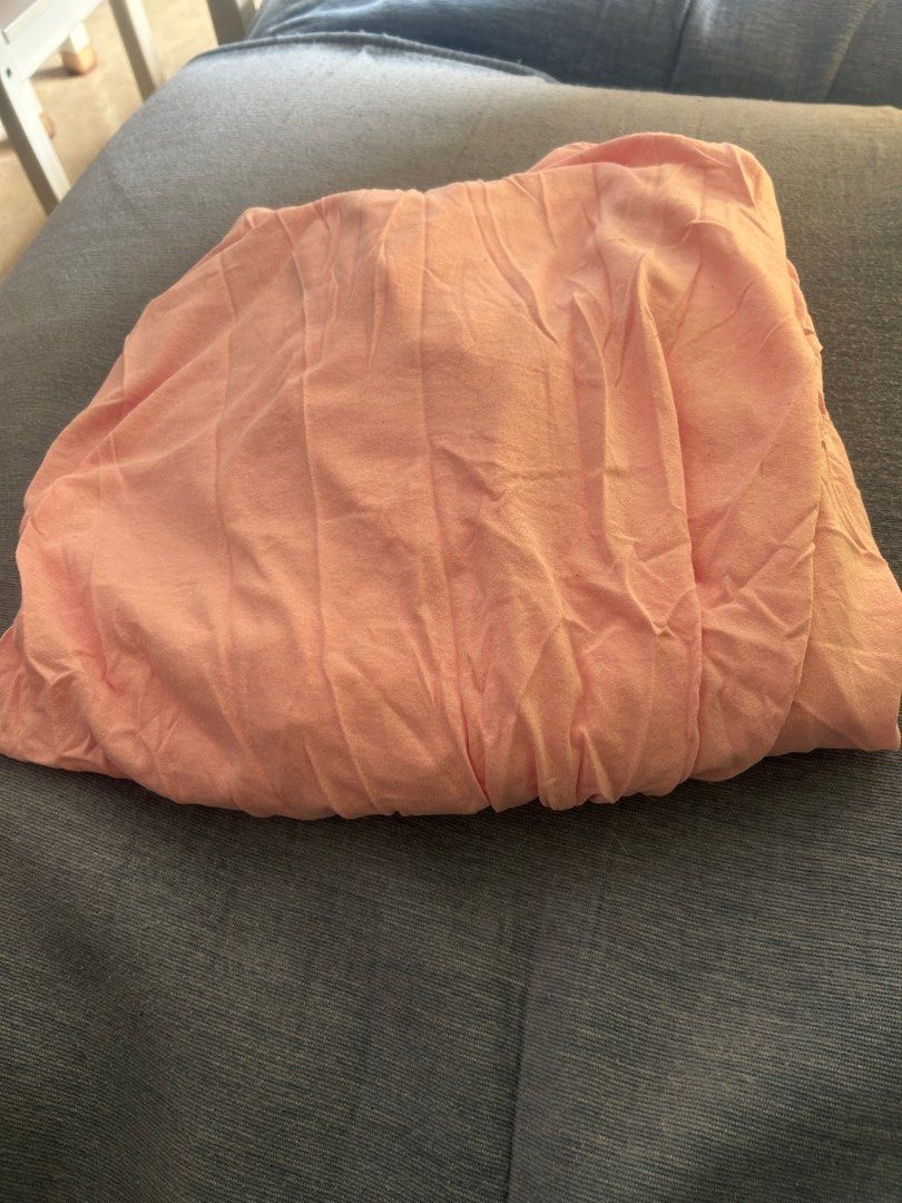 Peach Ikea bedsheet for Baby cribs (Category: Other Kids Furniture) located in Singapore. Submitted by care2sell01 (Listing ID 1376033230, Image 1). Description: Single-sized fitted sheet in peach color. Made from a soft, slightly textured fabric. Suitable for a standard single bed. The sheet is neatly folded and ready for use..