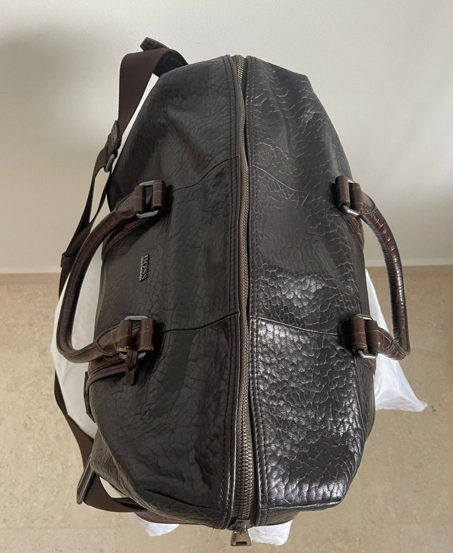 BOSS Leather Travel Duffle Bag (Category: Bags & Wallets) located in Singapore. Submitted by TreasureMan (Listing ID 1376709953, Image 3). Description: Stylish BOSS leather travel duffle bag. Features a two-tone design with dark brown textured leather and crocodile-embossed leather trim. Includes a detachable shoulder strap and multiple interior pockets. Durable and spacious..