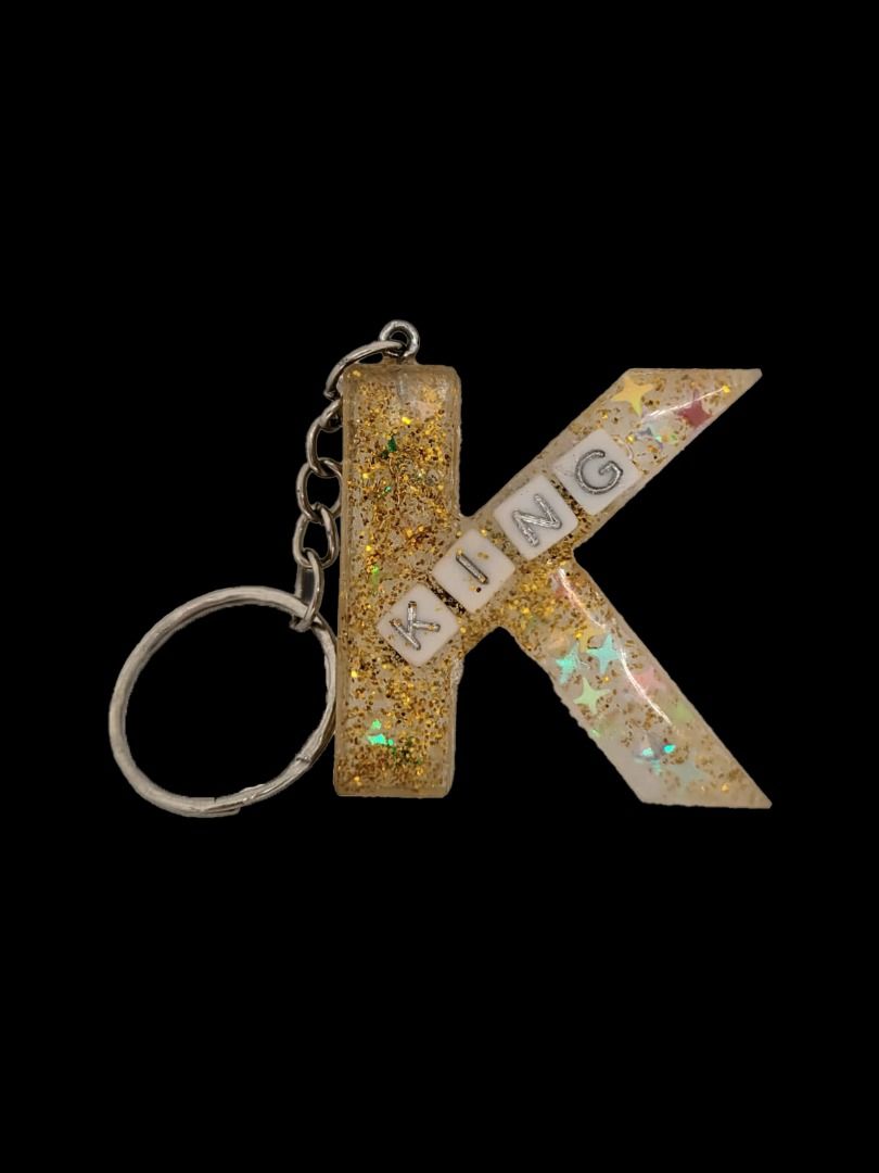 Custom Resin Letter Keychain - King (Category: Handmade Craft) located in Singapore. Submitted by missdiystore (Listing ID 1376908108, Image 2). Description: Hey there! Check out this super cute custom resin letter keychain! ✨ It's shaped like the letter K and has the word "KING" spelled out inside with tiny little letter beads. The resin itself is clear with gold glitter and iridescent stars – so pretty! It's got a nice, sturdy metal keyring, to