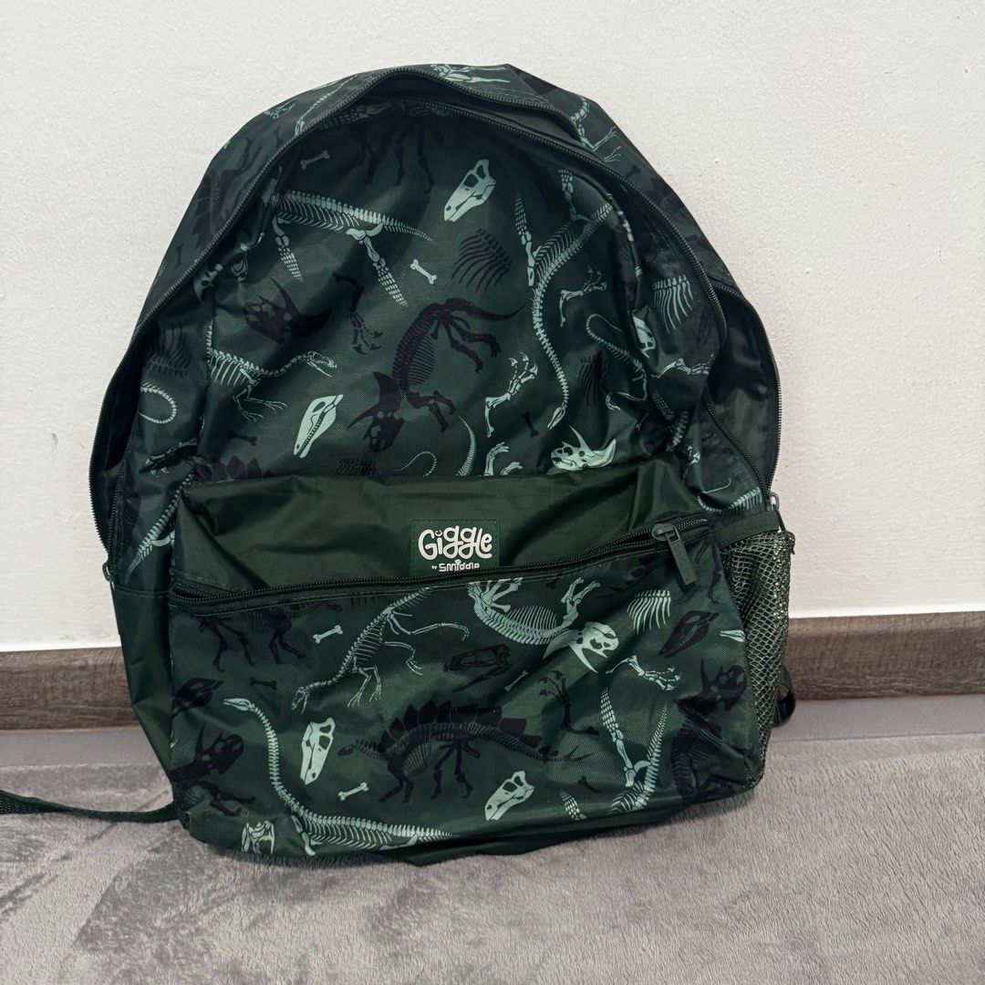 Smiggle Dinosaur Backpack (Category: Babies & Kids Fashion) located in Singapore. Submitted by northsider (Listing ID 1377093693, Image 1). Description: Smiggle backpack with a fun dinosaur skeleton print. Features multiple compartments for storage, including side mesh pockets. Adjustable straps for a comfortable fit. Perfect for school or travel. Used less than 5 times, almost new.