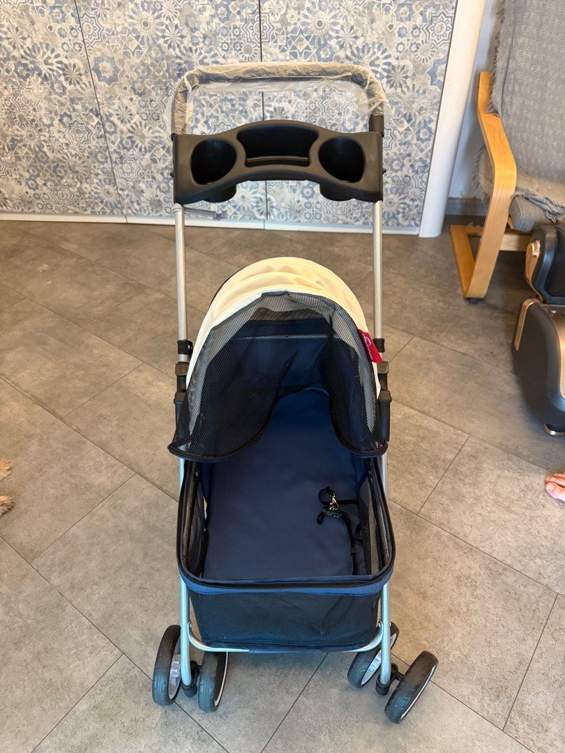 Foldable Pet Stroller. (Category: Homes & Other Pet Accessories) located in Singapore. Submitted by sxxxseansxxx (Listing ID 1377442507, Image 3). Description: This pet stroller is in excellent condition. It features a navy blue and cream canopy, a cup holder, and a storage basket. The stroller is easy to fold and unfold. Perfect for taking your furry friend on walks!.