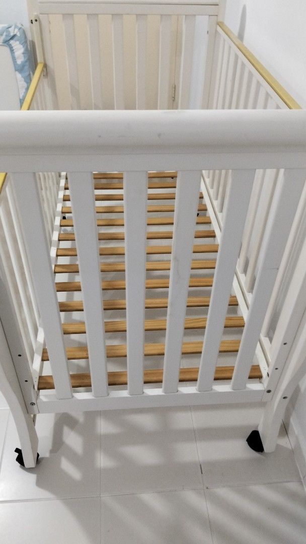 White Baby Cot with Wheels (Category: Cots & Cribs) located in Singapore. Submitted by metharita295178 (Listing ID 1377464532, Image 2). Description: - White baby cot - Wooden slats - Wheels for easy movement - Good condition - Suitable for newborns and young babies.